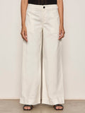 Someone wearing Sanctuary Clothing's "academy wide leg collagen" off-white trousers, a black textured top, and black open-toe sandals stands against a plain light background.