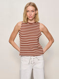 A blonde woman wears the Sanctuary Clothing campari tank clay stripe, a sleeveless brown and white striped top, paired with white lace-up waist pants, standing against a plain light background with her hands behind her back.