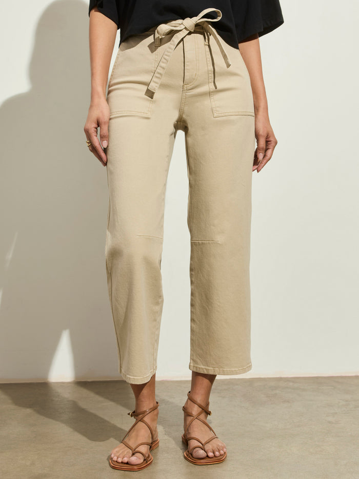 A person wearing the Sanctuary Clothing foundry pant khaki, paired with a black top and brown strappy sandals, stands against a light background.