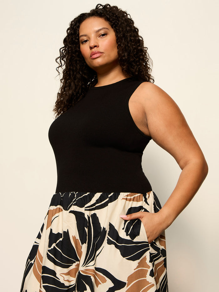A woman with curly hair models the Sanctuary Clothing sandbar mix media midi dress lotus with black (extended sizing), standing with one hand in her pocket against a plain background.