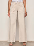 A person wears Sanctuary Clothing's Soft Polished Wide Leg Summer Sand trousers with a matching belt, paired with a white sleeveless top and open-toe sandals, standing against a neutral background.