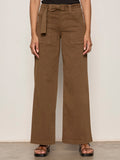 Someone stands against a light background, wearing Sanctuary Clothing’s "soft polished wide leg timber" high-waisted brown pants with a matching belt, paired with a black top and brown sandals. Only the body from shoulders down is visible.