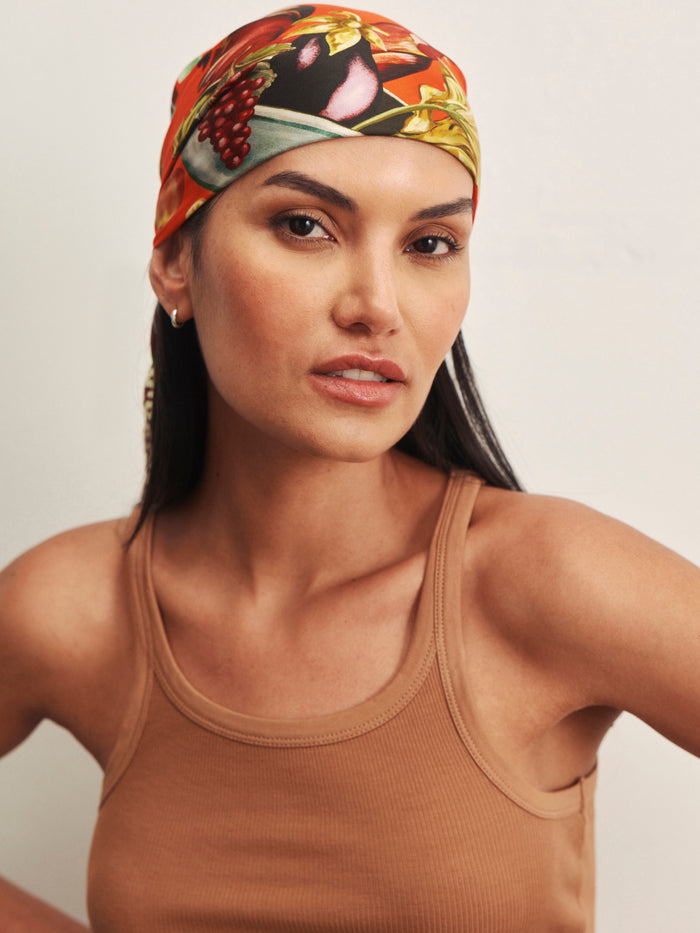 A woman models the Sanctuary Clothing sprinter rib tank in toasted coconut, paired with a colorful floral headscarf, as she looks confidently at the camera against a plain light background.