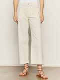 A person wearing Sanctuary Clothing's the marine jean bleached white pinstripe, styled with a white top and brown strappy sandals, stands against a plain background.