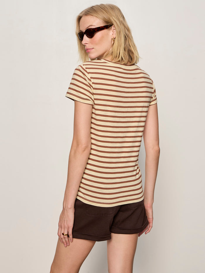 A woman with chin-length blonde hair in sunglasses wears the Sanctuary Clothing "the perfect tee choco banana stripe" as she faces away from the camera against a plain light background.