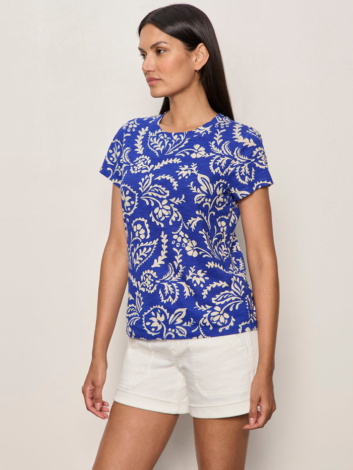 A woman wearing the Perfect Tee Portofino by Sanctuary Clothing stands against a light-colored wall, looking to the side.
